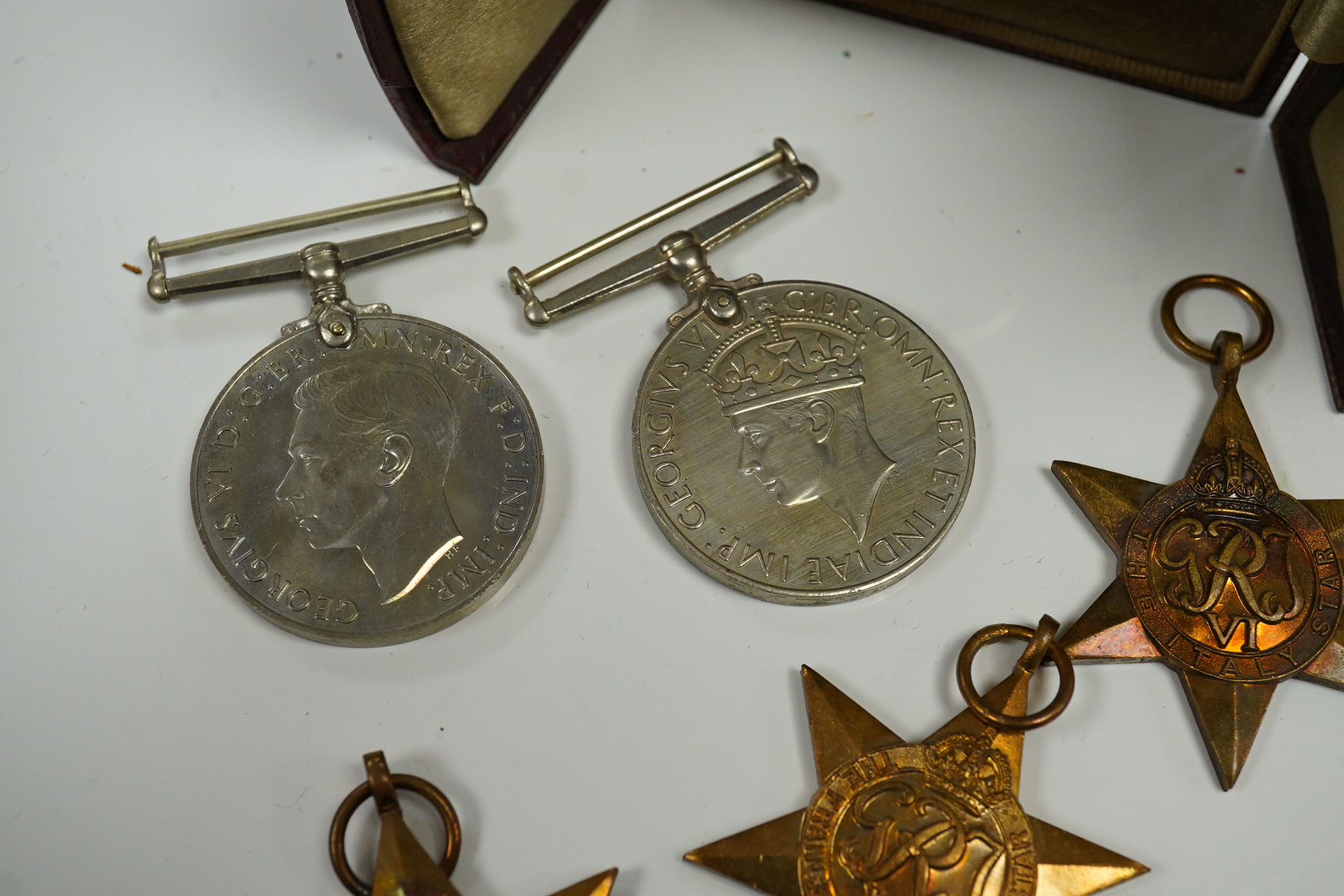 Five WWII medals including the Italy star, the France and Germany star, etc. and a cased miniature of a First World War officer in uniform, plus a leather cylindrical case. Condition - fair to good, significant chip to t